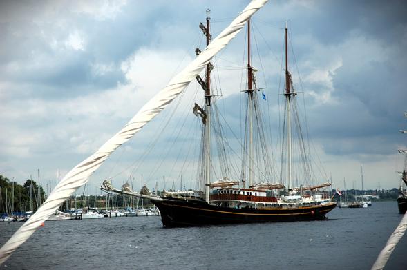 Dana aus dem niederländischen Kampen verwandelte sich vor etlichen Jahren in eine Barkentine namens goldene Löwin. 

Querformat, Farbe: Das Bild zeigt die "Golden Leeuw", ein großes, dreimastiges Segelschiff beim Auslaufen unter Motor aus einem Hafen. Im Hintergrund sind kleinere Segelboote und eine bewölkte Landschaft zu sehen. Der Blickwinkel ist von einem anderen Schiff aus, dessen Tauwerk im Vordergrund den Blick auf die "Golden Leeuw" teilweise verdeckt.