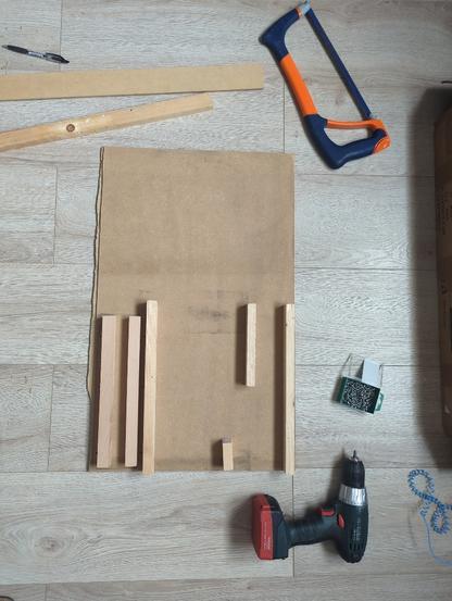 Un panneau rectangulaire (42 cm x 60 cm) de bois compressé, médium MDF, avec 6 petits tasseaux positionnés et fixés dans le sens de la longueur.
Une visseuse électrique, une boite de vis, une scie à métaux, un stylo.
