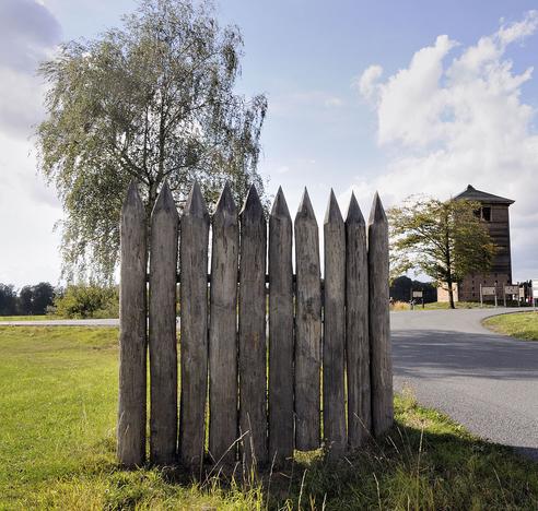 Limeswachtposten Wp 10/15, Rekonstruktion nahe der gesuchten Ortschaft.
Vorne befindet sich ein Stück rekronstruierte Palisade des ehemaligen Limes.
(Bild: DerHexer, Wikimedia Commons, CC-by-sa 4.0, 2012)
