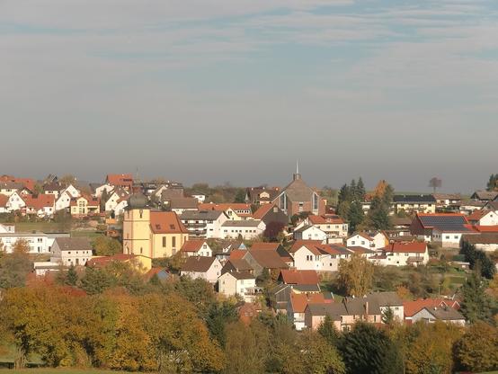 Teilansicht der gesuchten Ortschaft, die evangelische Laurentiuskirche ist links, die katholische Kirche Hl. Geist ist rechts zu erkennen.
(Bild: Wikimedia Commons, CC-BY-SA 3.0 nicht portiert“, „2.5 generisch“, „2.0 generisch“ und „1.0 generisch“, Urheber: V. 2010)