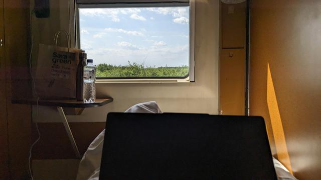 I'm sitting in a bed of a night train compartment. There's a laptop on my lap and summer landscape outside of the window.