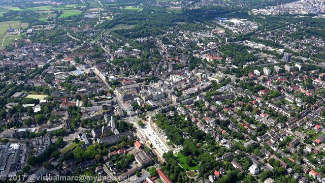 An aerial photo of Gelsenkirchen with many green places and trees between the houses.