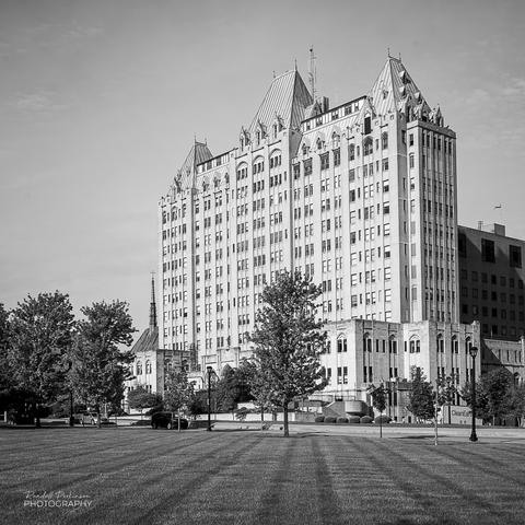 1933 Modern Gothic Revival style hospital building sits across the street from a park.