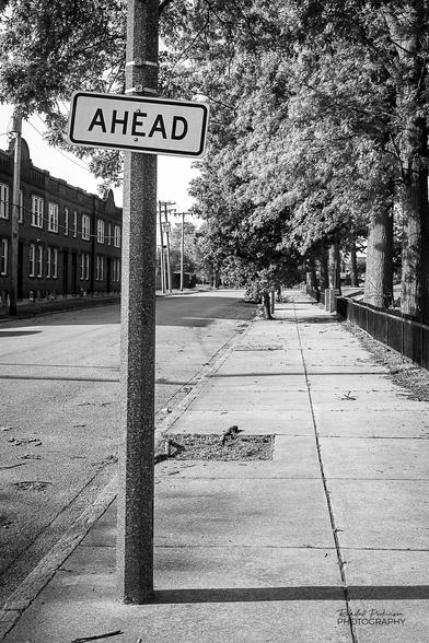 A street light pole has a single sign mounted to it that says "AHEAD".  There is a missing sign, so there is no way to know what is ahead of this location.