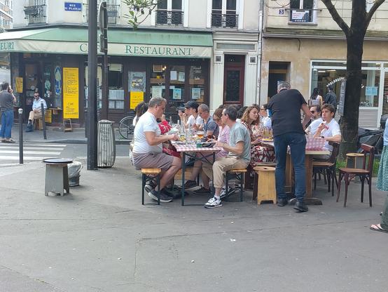 Bunch of people sitting outside a cafe.