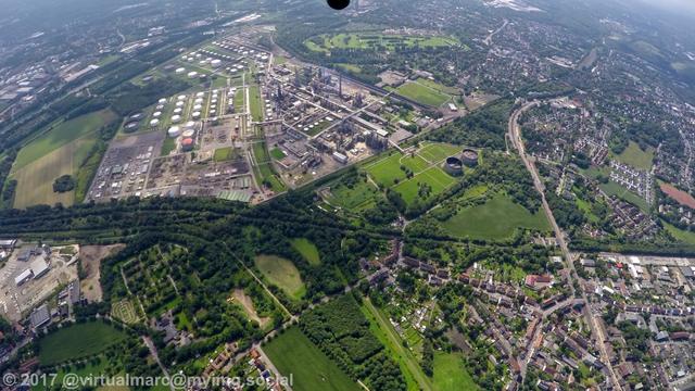 An aerial photo of Gelsenkirchen Horst, with the Beckhausen-Sutum cementry, including the Schalke Fan Feld, in the bottom left and the Coker BP Gelsenkirchen Horst rafinnery in the top. Green places and trees are all around.