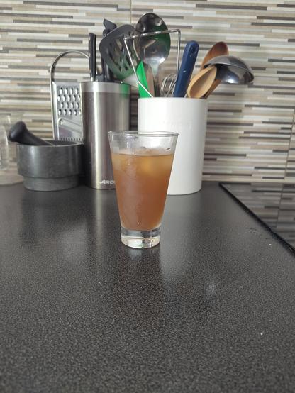 A glass of iced tea on a kitchen top.