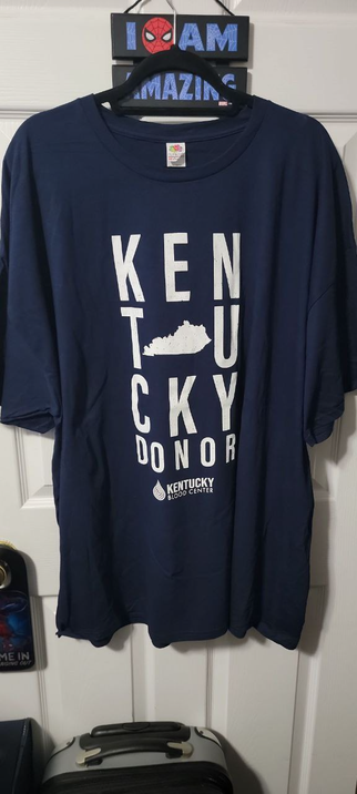 Blue T-Shirt with the letters KENTUCKY spelt out in a square with a map of Kentucky in the middle.
At the bottom is Kentucky Blood Center with their logo.