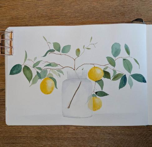 This is a watercolor painting of a lemon branch in a carafe like vase. This is painting in landscape format. The vase is centered and the branch extends up and reaches out to the right and left really accenting its landscape format. There are three roundish lemons on the branch two on the right; one high near the neck of the carafe, the other is nearer to the bottom of the carafe and is behind it so part of the lemon (and a leaf) is obscured by the glass but still visible. The one lemon on the left is out a little from the carafe and a little lower than the lemon on the top right.  The lemons have a highlight on the right side. The are lots of leaves along the branch's branchlets some larger (around the same size as the lemons just narrower) some tiny and every size inbetween. The leaves are varying shades of green some blue leaning and some yellow leaning. The branch which is visible in the glass carafe is a darker brown and lightens at the end of the branchlets.