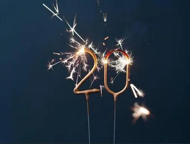 A festive sparkler candle forming the number "20," glowing against a dark background, symbolizing celebration.