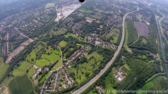 An aerial photo of the Schurenbach spoil heap (Schurenbachhalde) in Essen with many Trees around. A freeway (the A42) is in front of it.