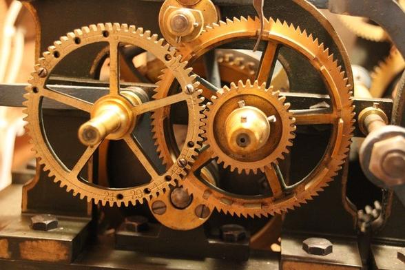 Une machinerie mécanique d'apparence anciennt constituée d'engrenages de teinte cuivrée.