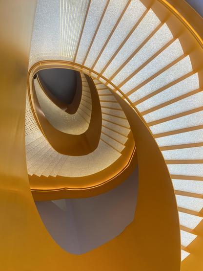 An orange staircase with light grey steps is spiraling downwards non symmetrically.