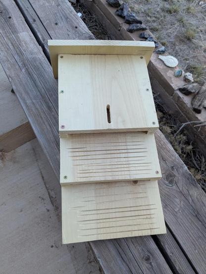 A 2-chambered bat box, not yet painted. It has a vertical slit for a vent in the front, and scoring on the inner boards to give bats little ledges to cling onto.