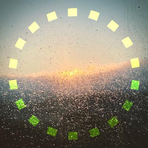 a dotted circle - the Reveil 12 logo -  a yellow circle of rectangular dashes 

in background, sun rising through our kitchen window that is now caked in salt after a week of wild storms