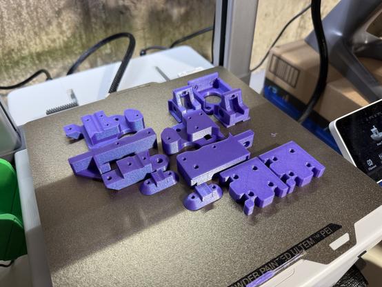 Somewhat iridescent purple printed parts on the bed of a 3D printer. The parts appear crisp and clean.
