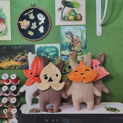 Cinq peluches Korogu avec des feuilles colorées, dans les tons oranges, jaunes et vert