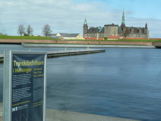 a view across the Helsingor harbour, with Kronborg Castle, of Hamlet fame, in the background. It is brick and stone, with a few pointed towers.