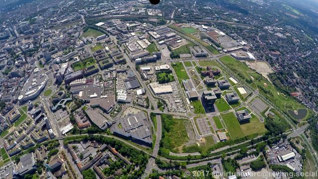 An aerial photo of the center of essen. The center of essen can be seen on the left side, with the Limbecker Place in the middle left. The Essen main station can be seen in the top left, together with most of the skyline of Essen.
On the right side you can see the Krupp quater, the headquater of the Thyssen Krupp Steel Company, with a big building looking liek a cube in a park.