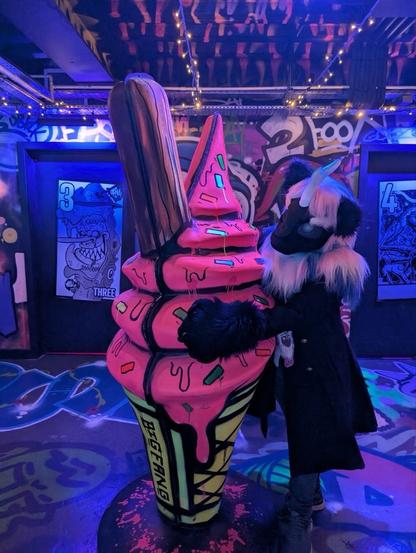 Noir (Nirik (Kirin) fursuit with white, pink and blue mane) hugs a giant pink ice cream.