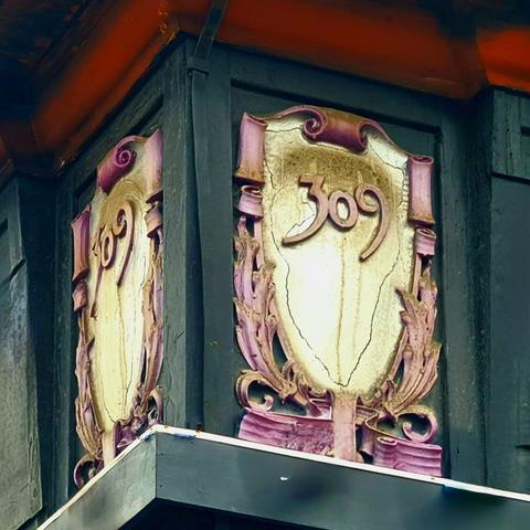 An Art Nouveau style decorative street number plaque on the corner of a late Victorian commercial building.