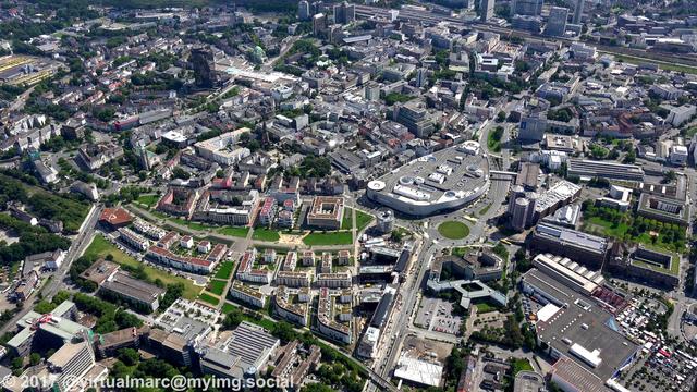 An aerial photo of the center of Essen.
You can see the Limbecker place, a big mall in the center of Essen.
Directly right of it is the CinemaxX Essen, it's Germanys biggest Multiplex Cinema with 5067 seats in 16 halls.
Below you see the buildings of the Funke Media Group next to the "new middle" living quaters.
In the top you can see the Essen Central station.
The black Y-Shaped building in the top left is the city hall of Essen.
In the top right of the city hall you can see the old synagogue.