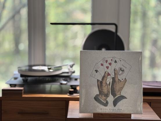 Bingo Hand Job - Live at the Borderline ‘91 LP cover.

A drawing of two hands holding a hand of cards.

The black LP plays on a Rega NAIA turntable to the left.