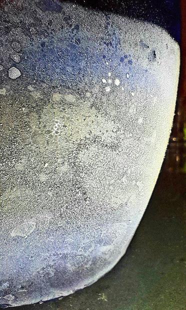 Ice condensing on the outside of a frozen blue tumbler containing subzero Jägermeißter resembles an ice moon.