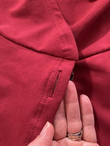 A bound or French buttonhole closeup placed vertically along the burgundy fleece hoodie opening.
