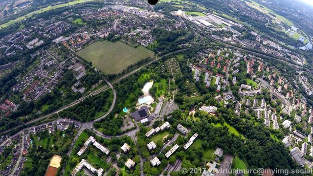 An aerial photo of the eastern part of essen with multiple living quaters in the green with trees all around. There is a swimming pool in the middle of the image.