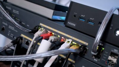 Close-up of network devices and cables, showcasing a gaming console, HDMI ports, and lit indicators on a patch panel.