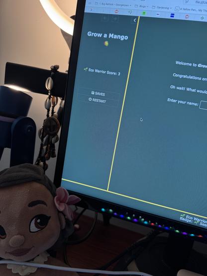 Computer screen with a green background and yellow borders. A small Moana doll is watching me while I work.