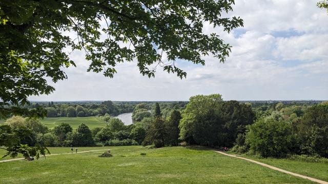 A view mostly of green fields and trees stretching to the horizon, with a river meandering through the middle.