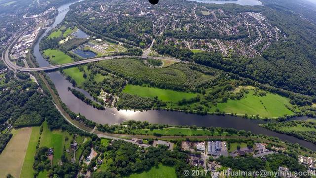 An aerial photo of the ruhr river with trees and a freeway (the A44) next to it. In the upper part you can see houses, this is Essen Heisingen.