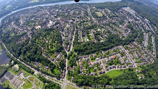 An aerial photo of Essen Heisingen with many houses and trees, sourrounded on three sides by the ruhr river.