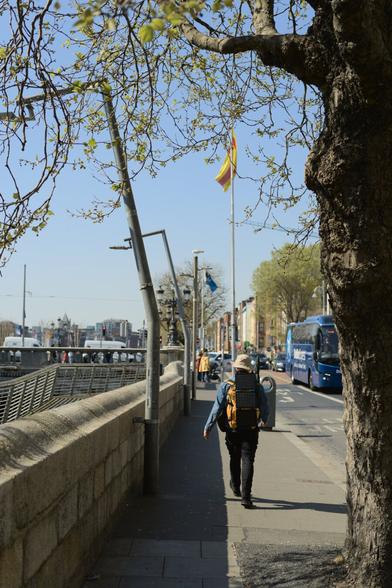 Man walking down a city footpath with solar panels on the exterior of his backpack
