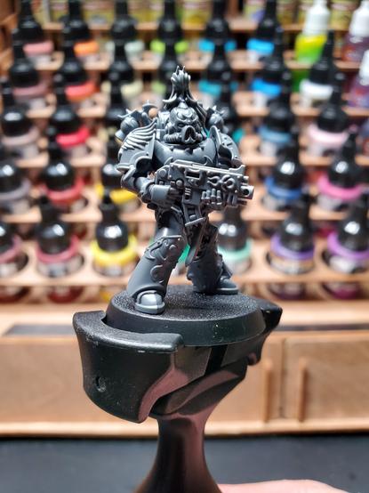 Photo of an assembled Emperor's Children Chaos Space Marine atop a paint handle.