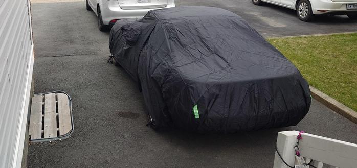 A red 1990 miata, unseen as under a black car cover