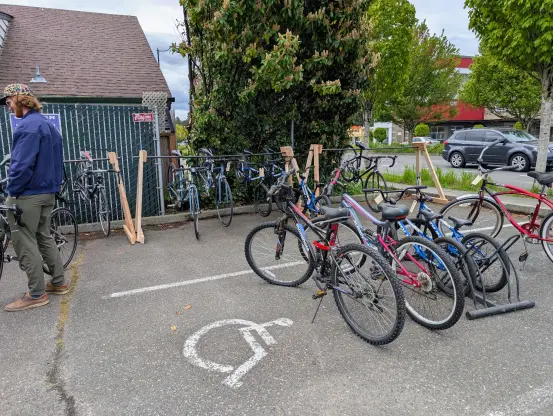 Outside Shoreline Tool Library. A few used bikes for sale on the right. A person on the left is talking to someone not in the picture.