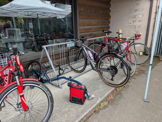 The cycle rack at the entrance to Shoreline Tool Library. A red trike is on the left, not locked to the rack. The rack has two bikes on it, one of which is my Marin.