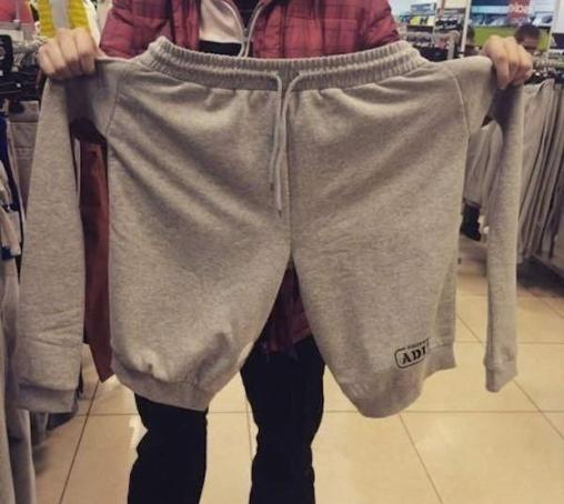 We're inside a retail store where a person is holding up a pair of shorts. Arms have been sewn on where the pockets should be. So the shorts have two legs and two arms.