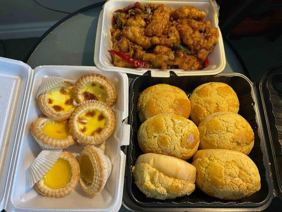fish fillets in a spicy sauce next to containers of egg tarts and pineapple buns, six each