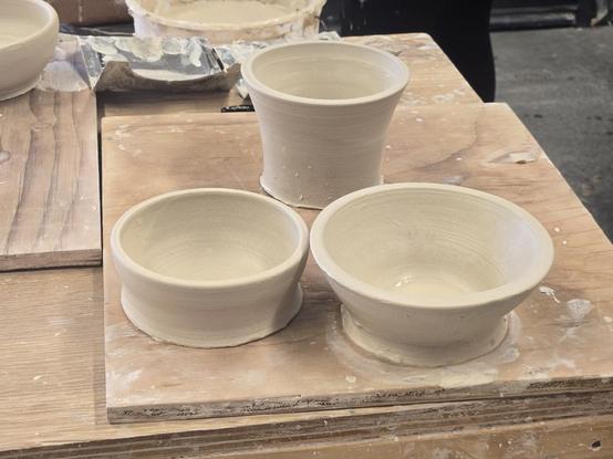Three light beige pots on a wooden board