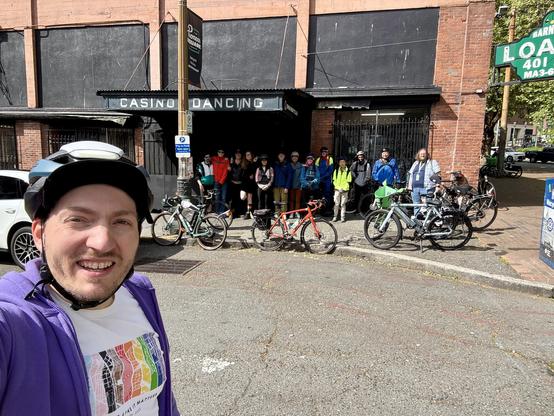 Selfie in front of a group of cyclists standing next to an awning with the text “Casino Dancing”