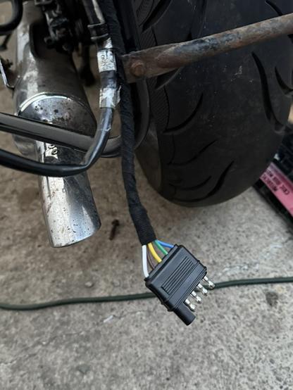 the rear end of a motorcycle, with the trailer wiring harness now properly wrapped and managed into position, with the 5-pin connector facing downwards.