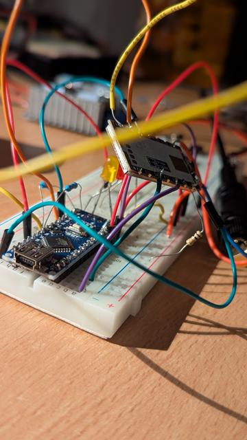 Close up shot of an Arduino nano on a breadboard, with a SA818 module suspended above it by a bunch of wires.