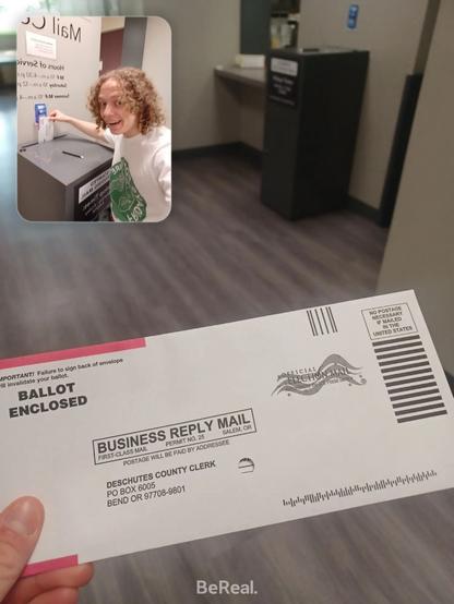A BeReal post. There's one front-facing photo taking up most of the image, and a second selfie-camera photo in the top left corner. The front-facing image is of an envelope labeled "Election Mail," being held. It's indoors. The selfie image is of a blonde, white man wearing a white shirt dropping the envelope in a gray mail deposit box. Also indoors.