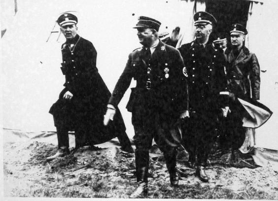 Röhm exits a marquee, Himmler directly behind him.
