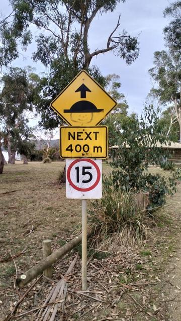 speed hump sign. a face has been painted on to give the impression the hump is a hat. 
Under a sign says "next 400m"