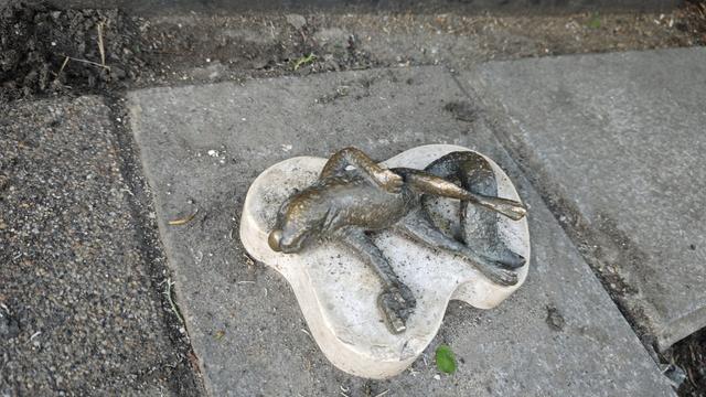In that red circled area is a very small statue and this photo is a detailed picture. On a white marble lies a bronze statue of a dead squirrel, holding a pistol in one hand.